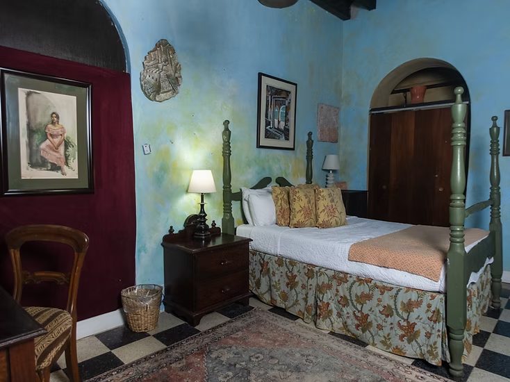 Another Artist Student Room at The Gallery Inn - a cozy room with blue walls, a carved wood bed, and antique furniture.