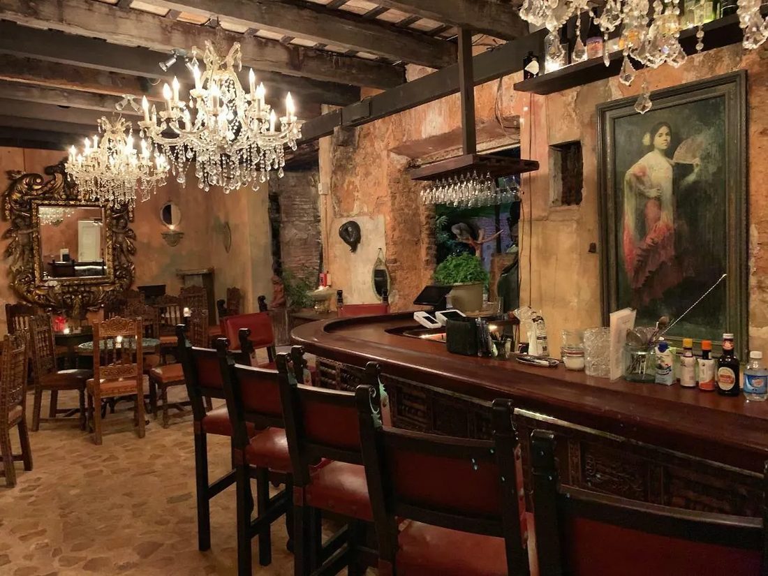 The Cannon Club bar - a carved wood counter, leather stools, crystal chandeliers, and Jan D'Esopo's art.