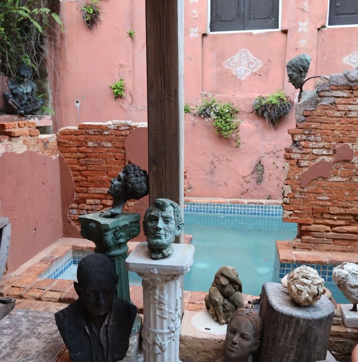 The sculpture pool, with Jan D'Esopo's bronze busts on pedestals around turquoise water and brick walls.