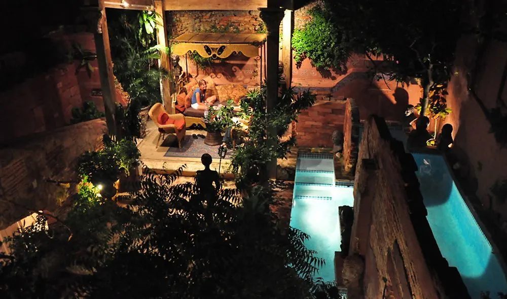 A second pool glowing turquoise by candlelight at night, surrounded by lantern-lit courtyard seating.