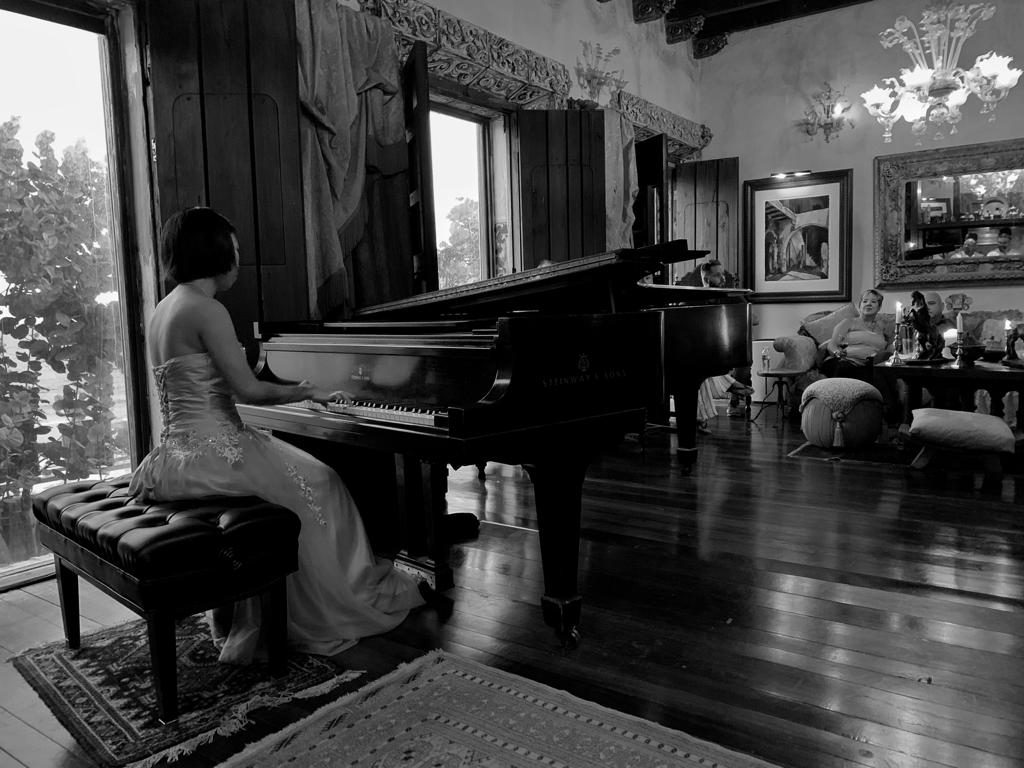 A pianist in a gown performing on a Steinway during a private concert.