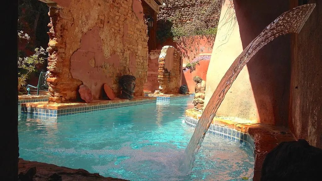 A pool with an arcing water feature against terracotta walls, warm and secluded.