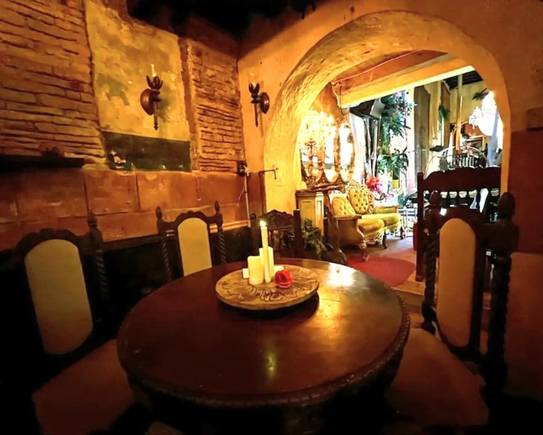 A candlelit corner of Studio Hall with antique chairs and warm light.