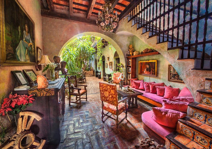 A rambling colonial hall at The Gallery Inn - terracotta walls, arches receding to a courtyard, a crystal chandelier, paintings, and rose-velvet seating.