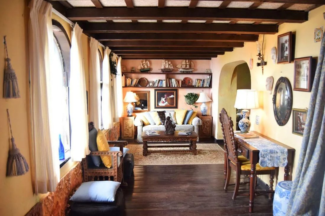 A Top Suite's private parlor at The Gallery Inn - a sofa and dining chairs beneath a wood-beam ceiling in warm light.