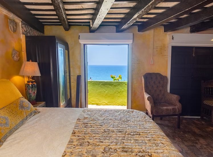A Vista Room at The Gallery Inn opening through shutter doors to a green lawn and the Atlantic beyond.